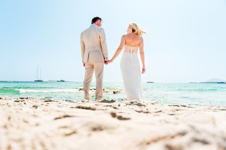 Hand in Hand geht das Brautpaar über den Sand nach der emotionalen Strandhochzeit - meer sardinien urlaub