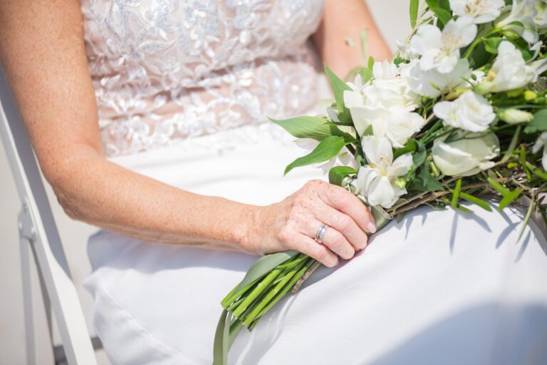 der bezaubernde Strauss ruht im Schoss der Braut während der Strandhochzeit - meer sardinien urlaub