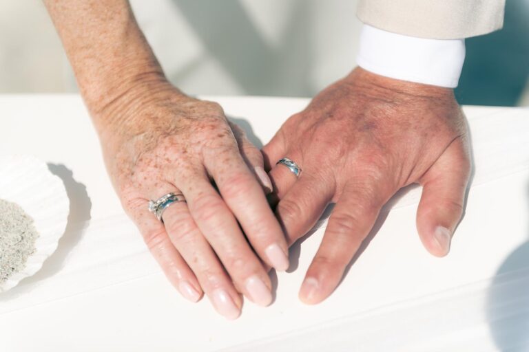 die Hände des Brautpaares mit den frischen Trauringen, Strandhochzeit - meer sardinien urlaub