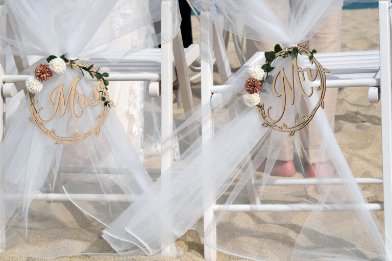 die-festlich-geschmückten-Stühle-des-Brautpaares-während-der-Strandhochzeit---meer-sardinien-urlaub