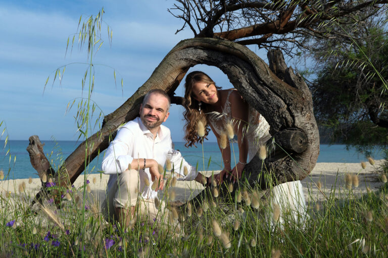 ein-knorriger-Stamm-als-natürlicher-Rahmen-beim-Paarshooting,-Strandhochzeit---meer-sardinien-urlaub