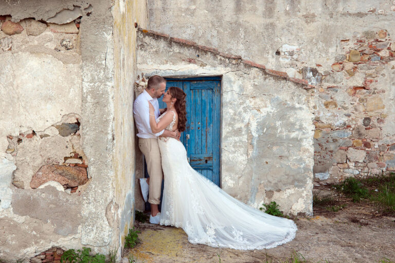 küssendes-Brautpaar-vor-einer-schönen,-blauen-Tür-eines-antiken-Gebäudes,-Strandhochzeit---meer-sardinien-urlaub