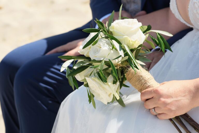 voler Stolz und Aufregung hält die Braut ihren Strauss während der Strandhochzeit - meer sardinien urlaub