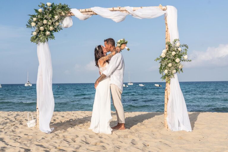 das oberglückliche Paar unter dem Trauungsbogen nach der Strandhochzeit - meer sardinien urlaub