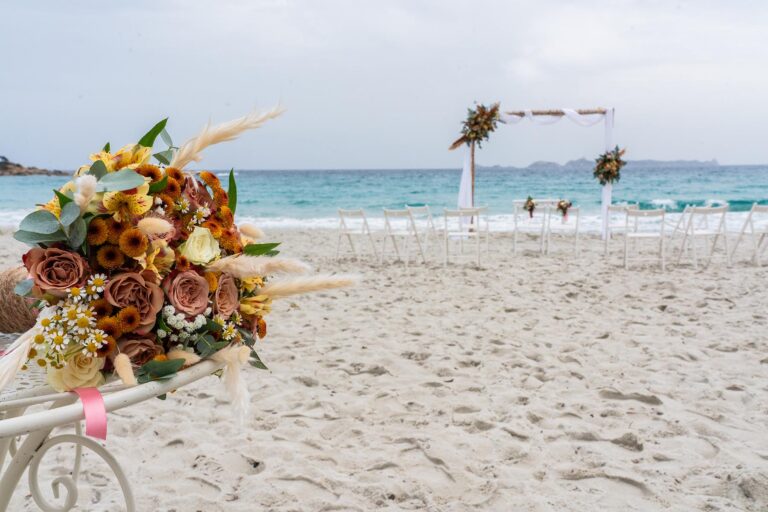 der Brautstrauss und im Hintergrund der geschmückte Trauungsbogen für die Strandhochzeit - meer sardinien urlaub