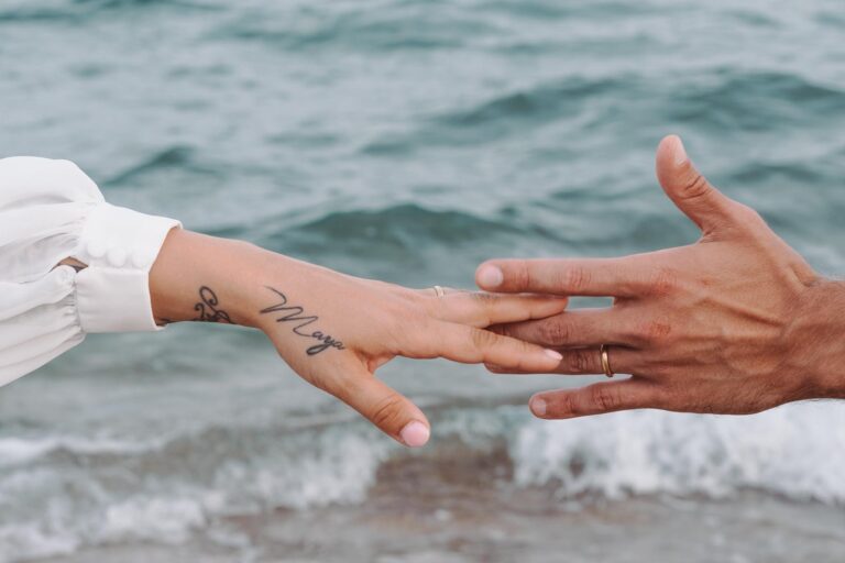 die Hände mit den Trauringen vor dem wundervollen Meer, Strandhochzeit - meer sardinien urlaub