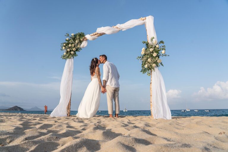 ein Kuß unter dem Trauungsbogen nach der Strandhochzeit - meer sardinien urlaub