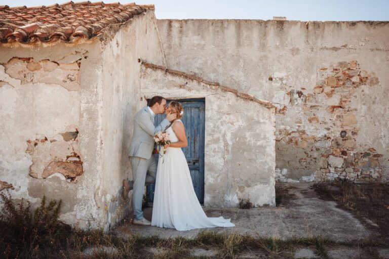 ein zarter Kuss vor einem antiken Gebäude nach der Strandhochzeit - meer sardinien urlaub