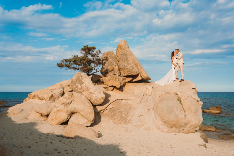 Brautpaar-auf-einem-Felsen-mit-knorrigem-Wacholderbaum-nach-der-Strandhochzeit---meer-sardinien-urlaub