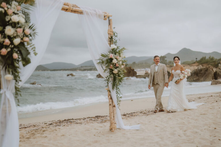 Brautpaar-geht-zum-Traubogen,-Strandhochzeit---meer-sardinien-urlaub