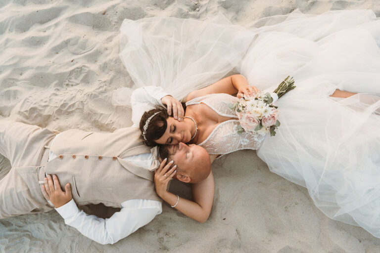 Brautpaar-liegend-am-Strand-nach-der-Trauung-im-Standesamt---meer-sardinien-urlaub