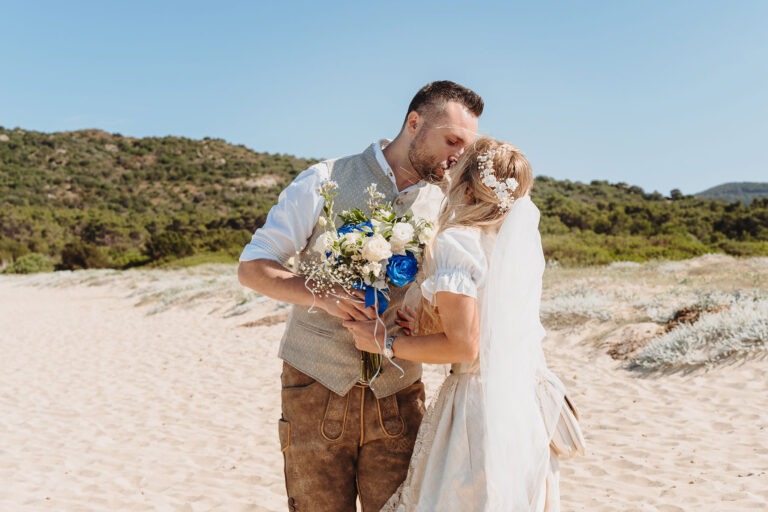 First-Look-mit-Übergabe-des-Brautstrausses-und-Kuss-vor-der-Strandhochzeit---meer-sardinien-urlaub