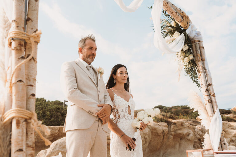 andächtig-verfolgt-das-Brautpaar-unter-dem-Traubogen-die-Zeremonie,-Strandhochzeit---meer-sardinien-urlaub