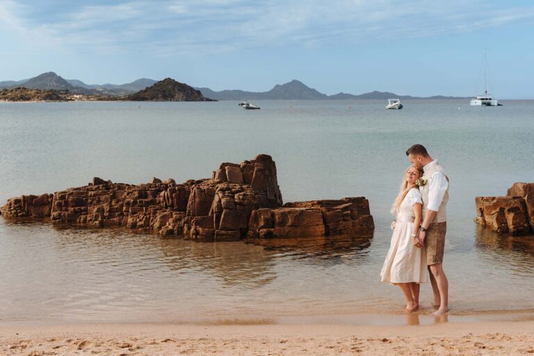 das-Brautpaar-am-Ufer-vor-malerischen-Felsen,-Strandhochzeit---meer-sardinien-urlaub
