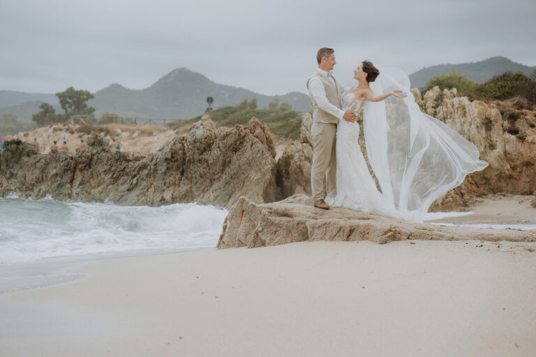 das-Brautpaar-auf-den-Felsen-am-Sandstrand-während-des-Paarshootings,-Strandhochzeit---meer-sardinien-urlaub