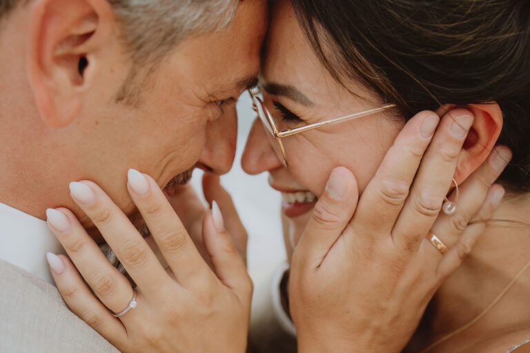 das-Brautpaar-blickt-sich-glücklich-lachend-in-die-Augen,-Strandhochzeit---meer-sardinien-urlaub