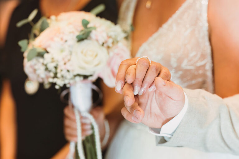 das-Brautpaar-hält-sich-während-der-Zermonie-liebevoll-die-Hand,-Trauung-im-Standesamt---meer-sardinien-urlaub