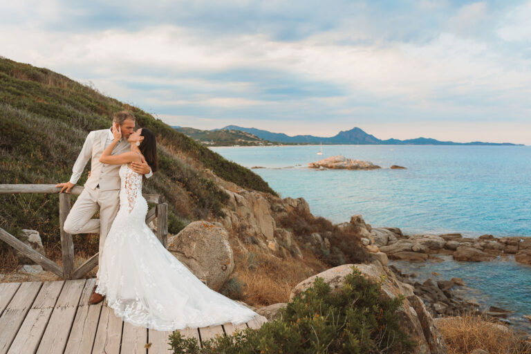 das-Brautpaar-küsst-sich-vor-einem-atemberaubenden-Küstenpanorama-während-des-Paar-Shootings,-Strandhochzeit---meer-sardinien-urlaub