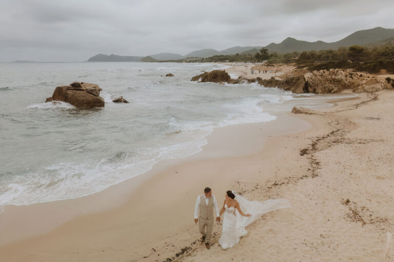 das-Brautpaar-spaziert-am-Traumstrand-entlang,-Strandhochzeit---meer-sardinien-urlaub