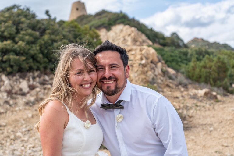 das freudestrahlende Brautpaar mit Sarazenenturm im Hintergrund, freie Trauung - meer sardinien urlaub
