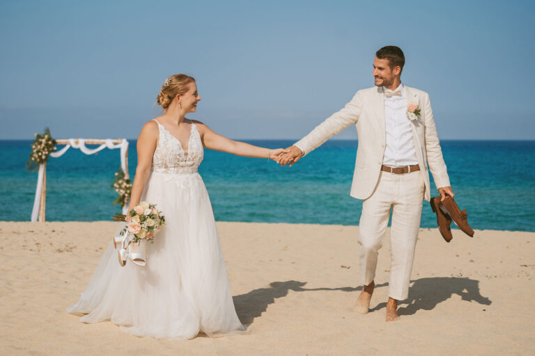 das-glücklich-vermählte-Paar-mit-Traubogen-im-Hintergrund-nach-der-Strandhochzeit---meer-sardinien-urlaub