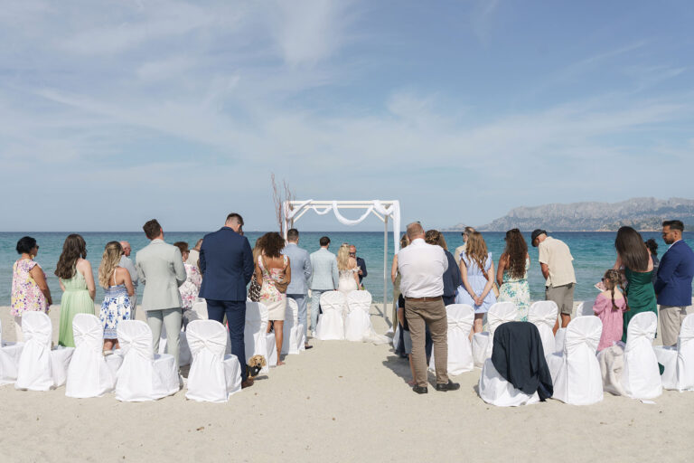 der-Höhepunkt-der-Zeremonie-wird-durch-die-stehende-Haltung-aller-Gäste-unterstrichen,-Strandhochzeit---meer-sardinien-urlaub