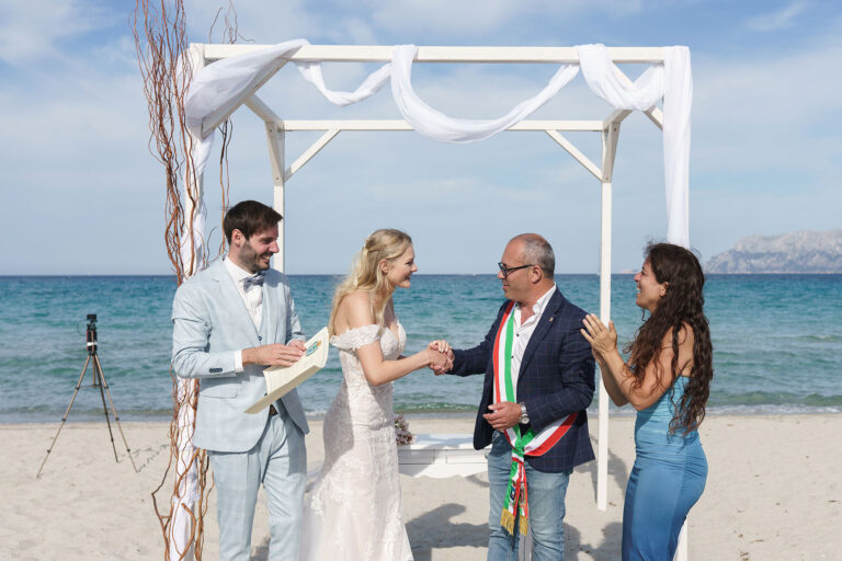 der-Standesbeamter-gratuliert-herzlich-dem-frisch-vermählten-Paar,-Strandhochzeit---meer-sardinien-urlaub