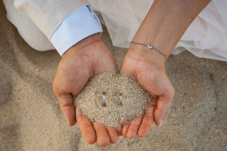 die-Hände-des-Brautpaares-zeigen-ihre-Trauringe,-Strandhochzeit---meer-sardinien-urlaub