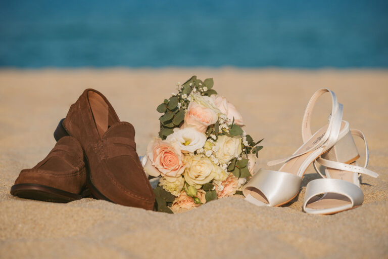 die-Schuhe-des-Brautpaares-mit-Brautstrauss-am-Strand-vor-dem-blau-glitzernden-Meer,-Strandhochzeit---meer-sardinien-urlaub