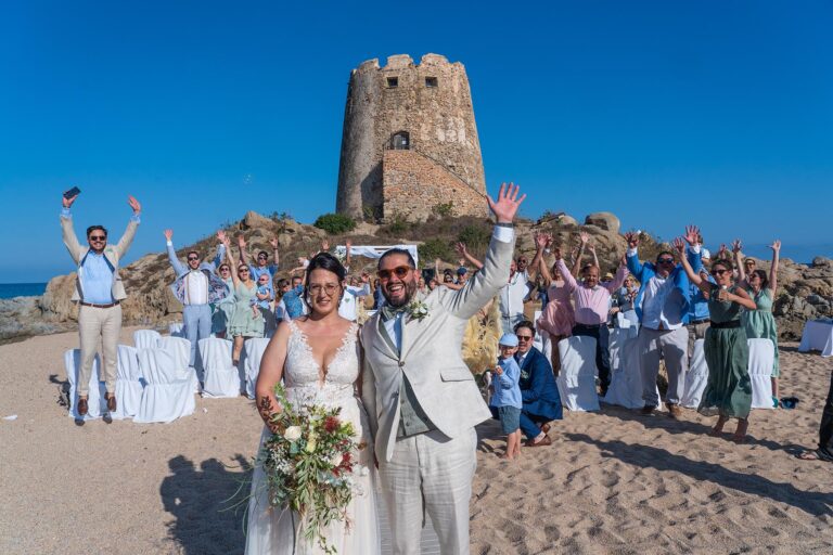 ein fröhliches Gruppenfoto der Hochzeitsgesellschaft am Strand vor dem malerischen Sarazenenturm - meer sardinien urlaub