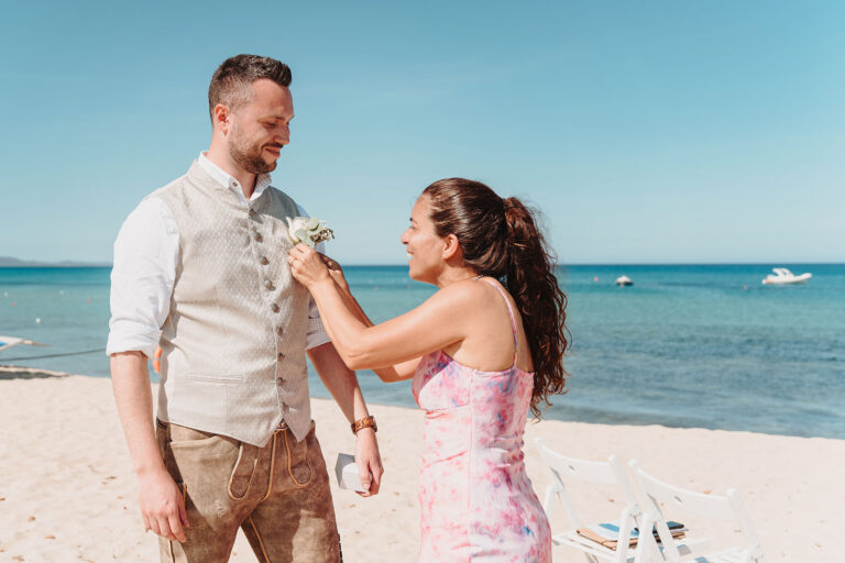 noch-kurz-den-Knopflochstecker-vor-der-Strandhochzeit-befestigen---meer-sardinien-urlaub