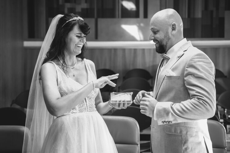 noch-nahezu-ungläubig-betrachtet-das-Brautpaar-die-Eheringe,-Trauung-im-Standesamt---meer-sardinien-urlaub