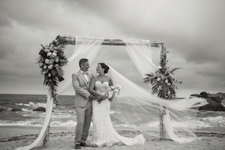 romantisches-Schwarz-Weiss-Bild-des-Brautpaares-unter-dem-Traubogen,-Strandhochzeit---meer-sardinien-urlaub