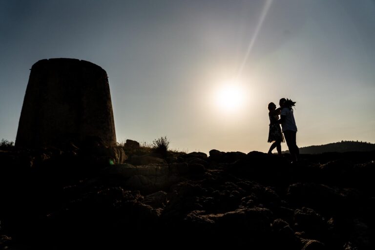 schönes Bild des Brautpaares mit Sarazenenturm im Gegenlicht im Anschluss an die rechtsgültige Trauung am Meer - meer sardinien urlaub