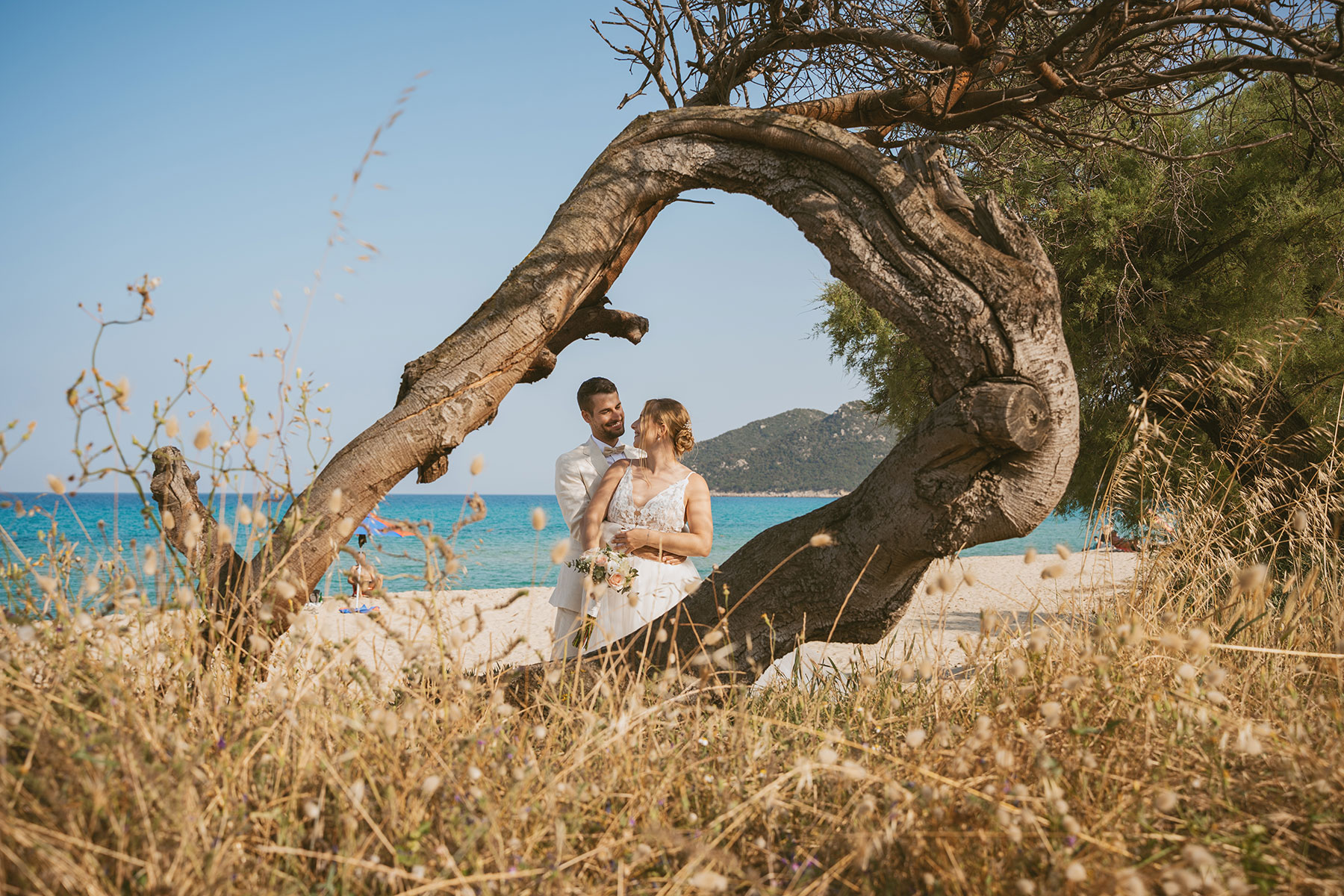 Glückliches Hochzeitspaar an einer Strandlocation für eine Hochzeit auf Sardinien mit Blick aufs Meer