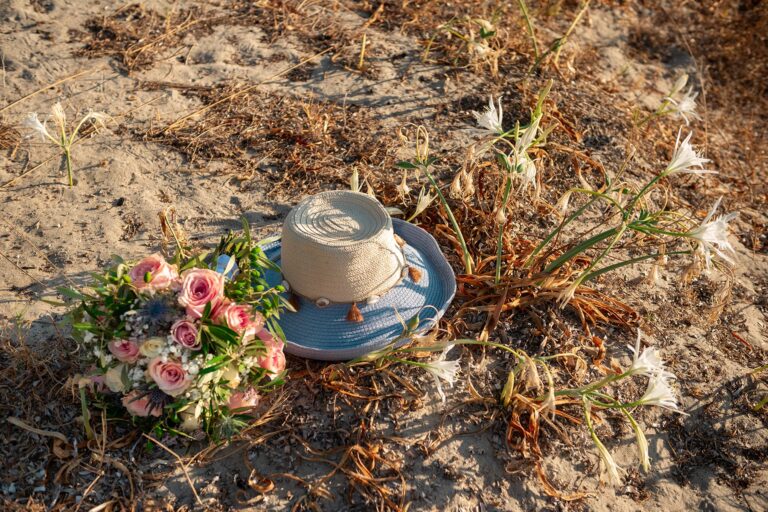 Brautstrauß-und-Hut-neben-zauberhaften-Strandlilien,-Strandhochzeit---meer-sardinien-urlaub