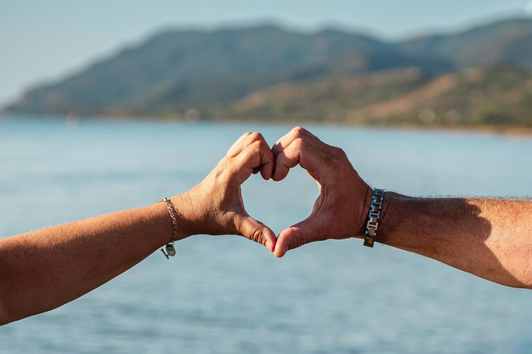 die-Hände-des-Brautpaares-formen-ein-Herz-vor-dem-Meer,-Strandhochzeit---meer-sardinien-urlaub