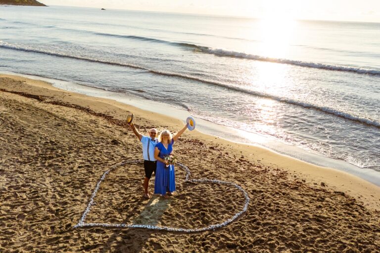 glücklich-grüßt-das-Brautpaar-am-Strand-die-Drohne,-Strandhochzeit---meer-sardinien-urlaub