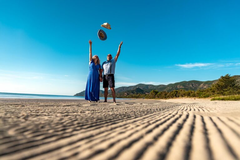 glücklich-wirft-das-Brautpaar-ihre-Hüte-in-die-Luft,-Strandhochzeit---meer-sardinien-urlaub