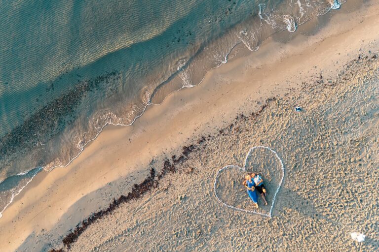 tolle-Drohnenaufnahme-des-auf-dem-Sand-liegenden-Brautpaares-nach-Strandhochzeit---meer-sardinien-urlaub