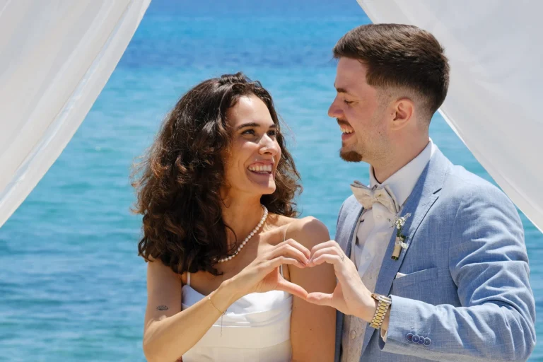 Brautpaar formt ein Herz mit den Händen, Strandhochzeit, meer sardinien urlaub