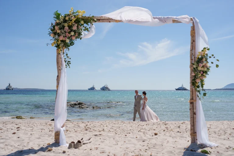 Brautpaar spaziert hinter dem Traubogen, Strandhochzeit, meer sardinien urlaub