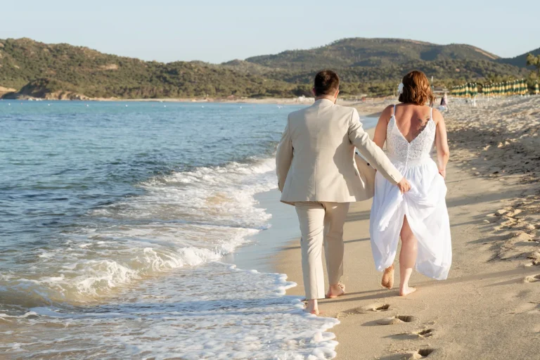das Brautpaar spaziert am Ufer entlang, Strandhochzeit - meer sardinien urlaub
