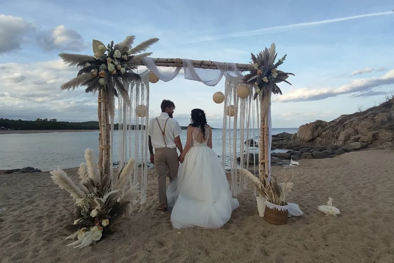 das Brautpaar unter dem Traubogen in den ersten Abendstunden, Strandhochzeit - meer sardinien urlaub