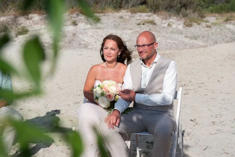 das sitzende Brautpaar während der Zeremonie, Strandhochzeit - meer sardinien urlaub