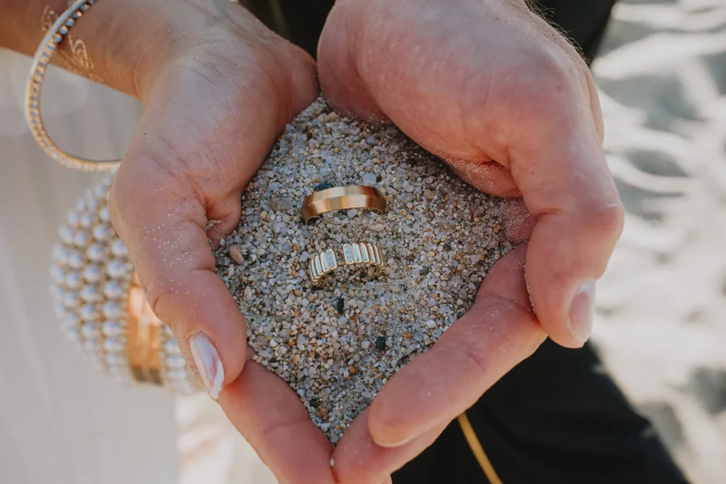 die Hände des Brautpaares halten die Ringe, Strandhochzeit, meer sardinien urlaub