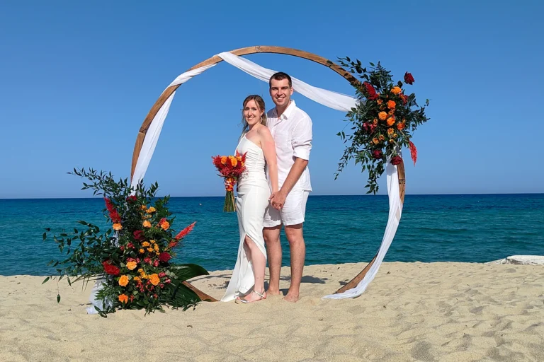ein hübsches Paarbild vor dem geschmückten, runden Traubogen, Strandhochzeit, meer sardinien urlaub