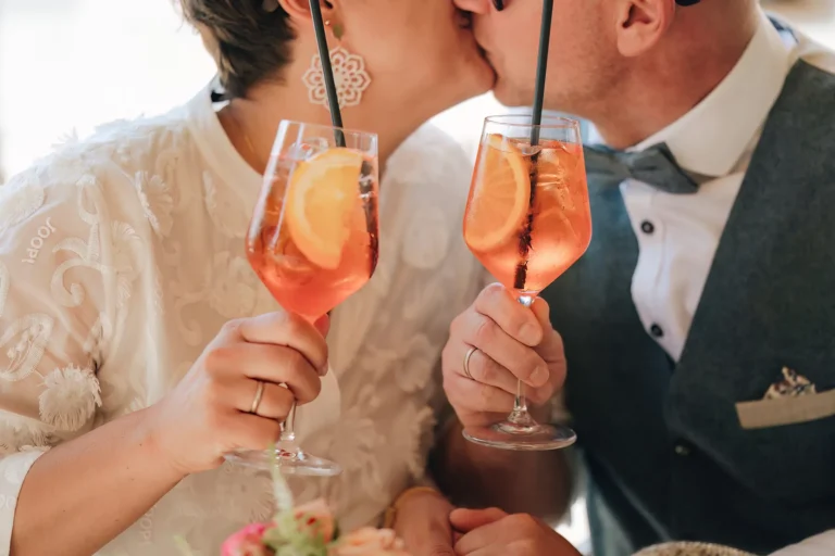 küssendes Brautpaar mit zwei Spritz-Gläsern in der Hand, Trauung - meer sardinien urlaub