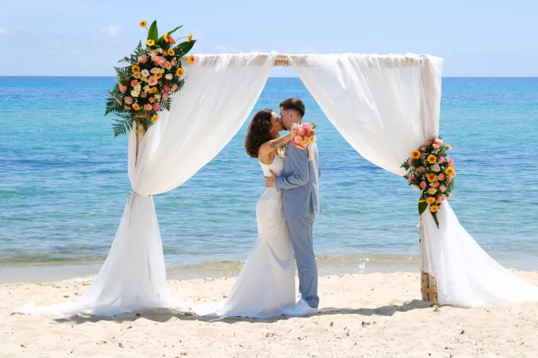 küssendes Brautpaar unter dem Traubogen, Strandhochzeit, meer sardinien urlaub