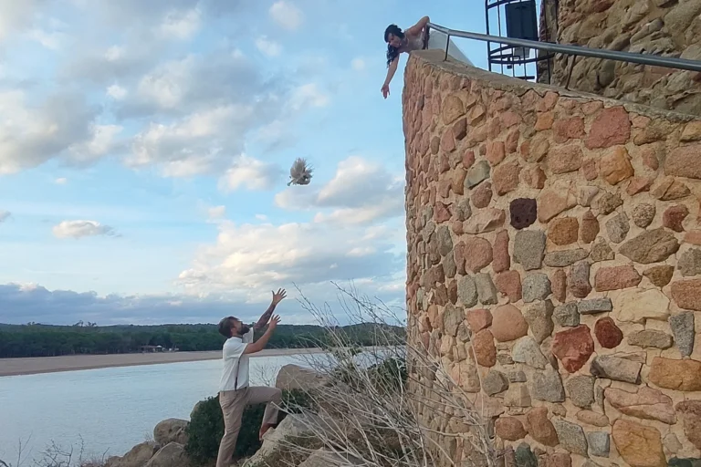 spielerisch wirft die Braut dem Bräutigam vom Küstenturm den Brautstrauß zu, Strandhochzeit - meer sardinien urlaub
